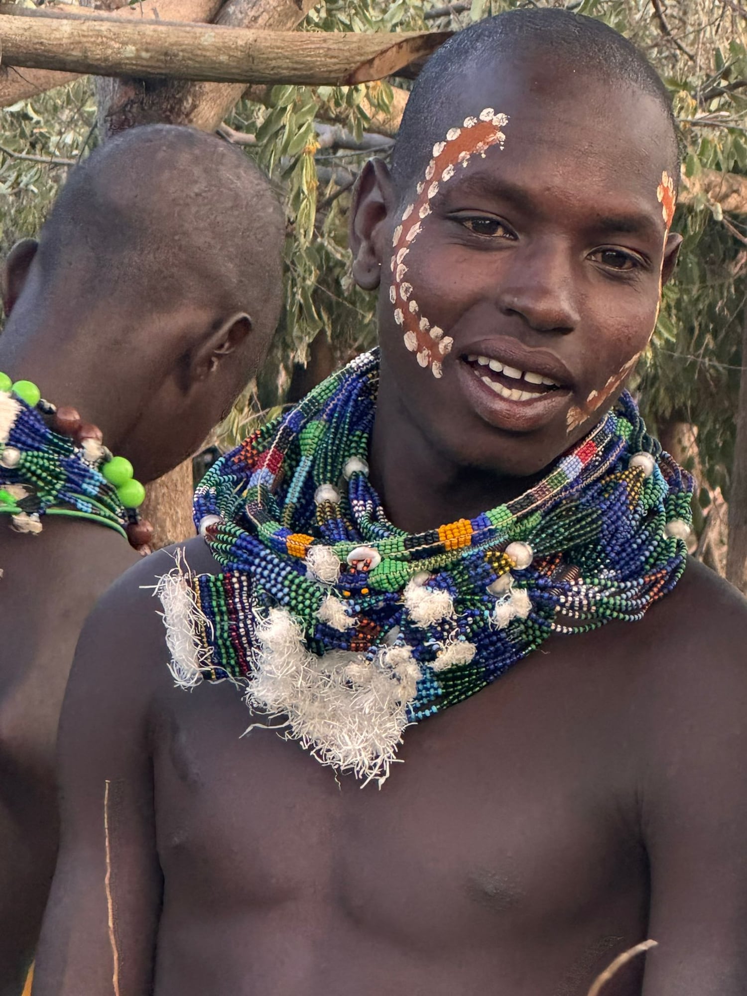 A young man in beaded necklaces laughing, Lower Omo